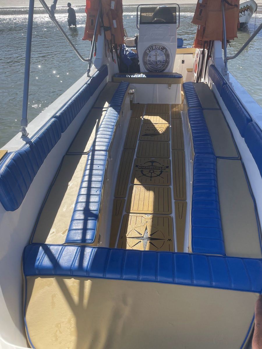 Convés do barco Puruca Passeios Náuticos (@barcopuruca) na Barra do Sahy com bancos azuis estofados, piso EVA e coletes salva-vidas